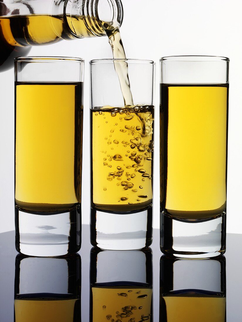 Brauner Rum in drei Gläser eingiessen
