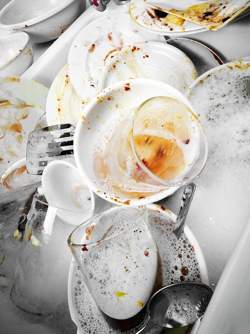 Dirty plates, glasses and cutlery in washing-up water
