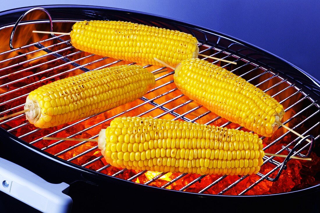 Four cobs of corn on barbecue
