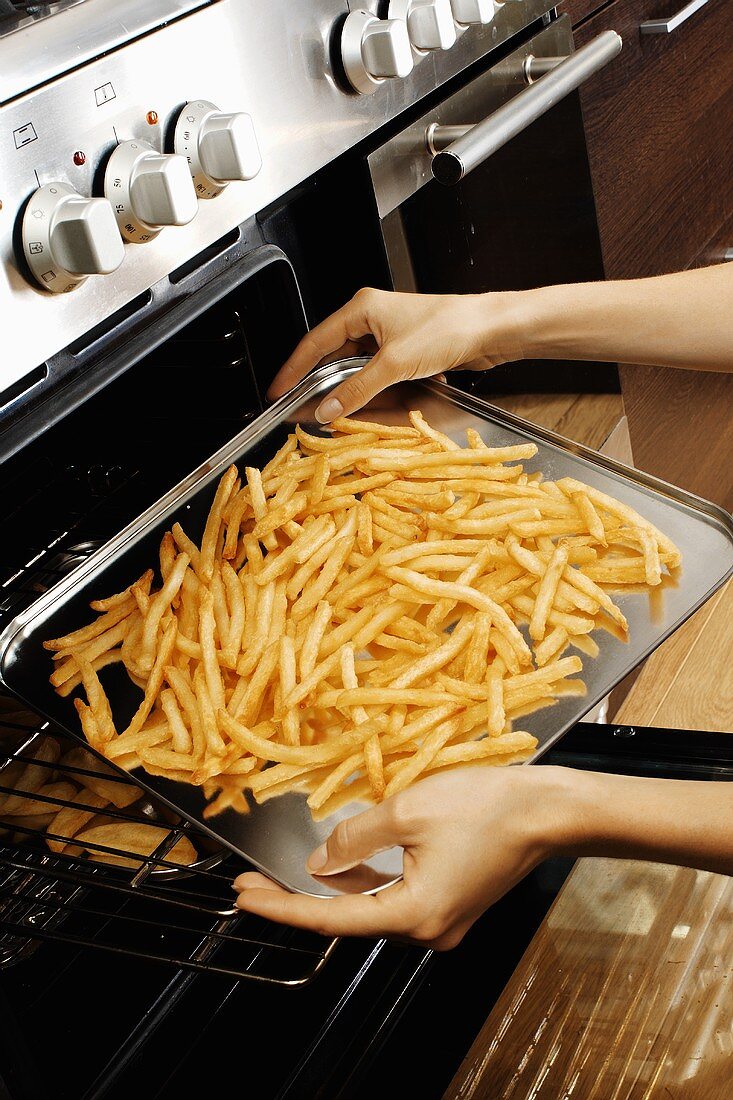 Taking a tray of chips out of the oven