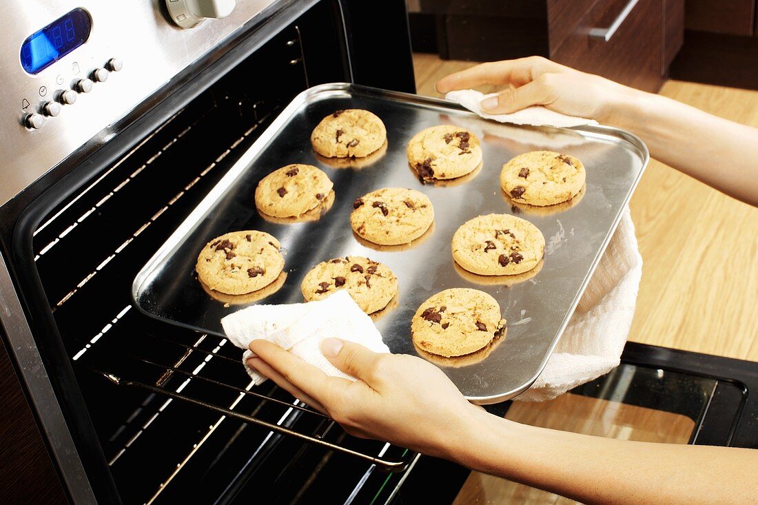 Taking chocolate chip cookies out of the oven