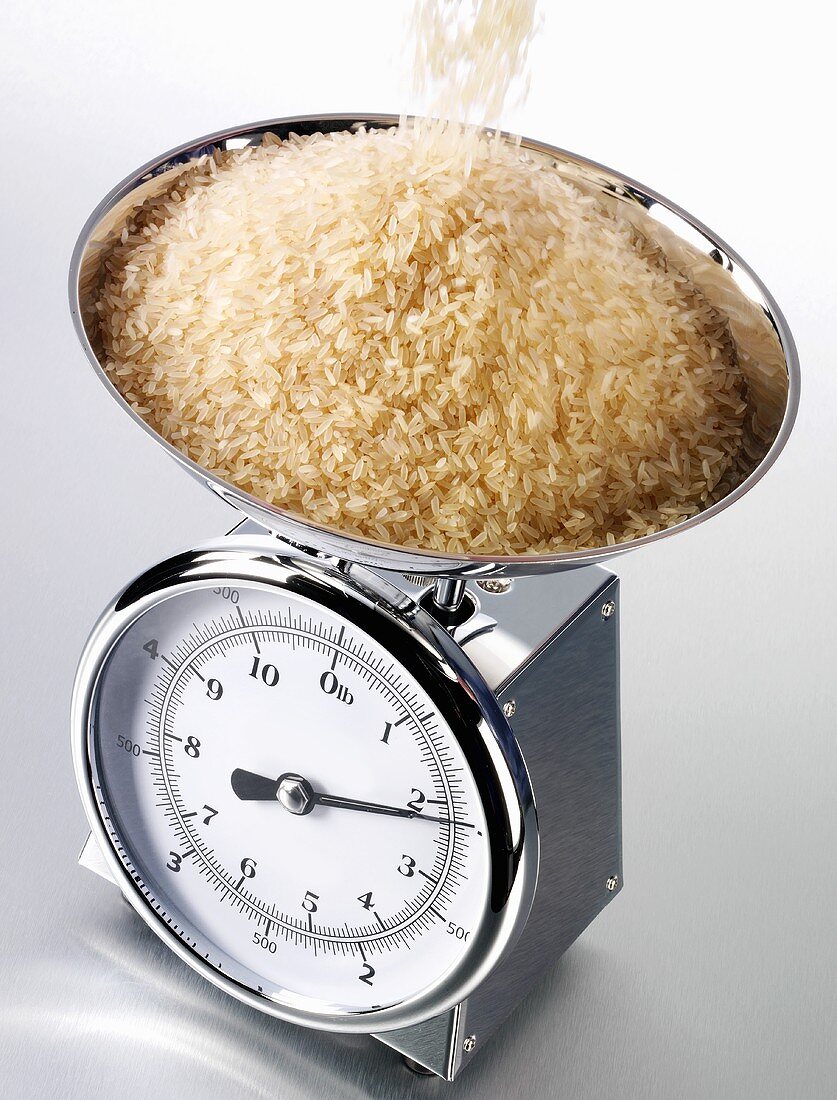 Reis auf eine Küchenwaage schütten