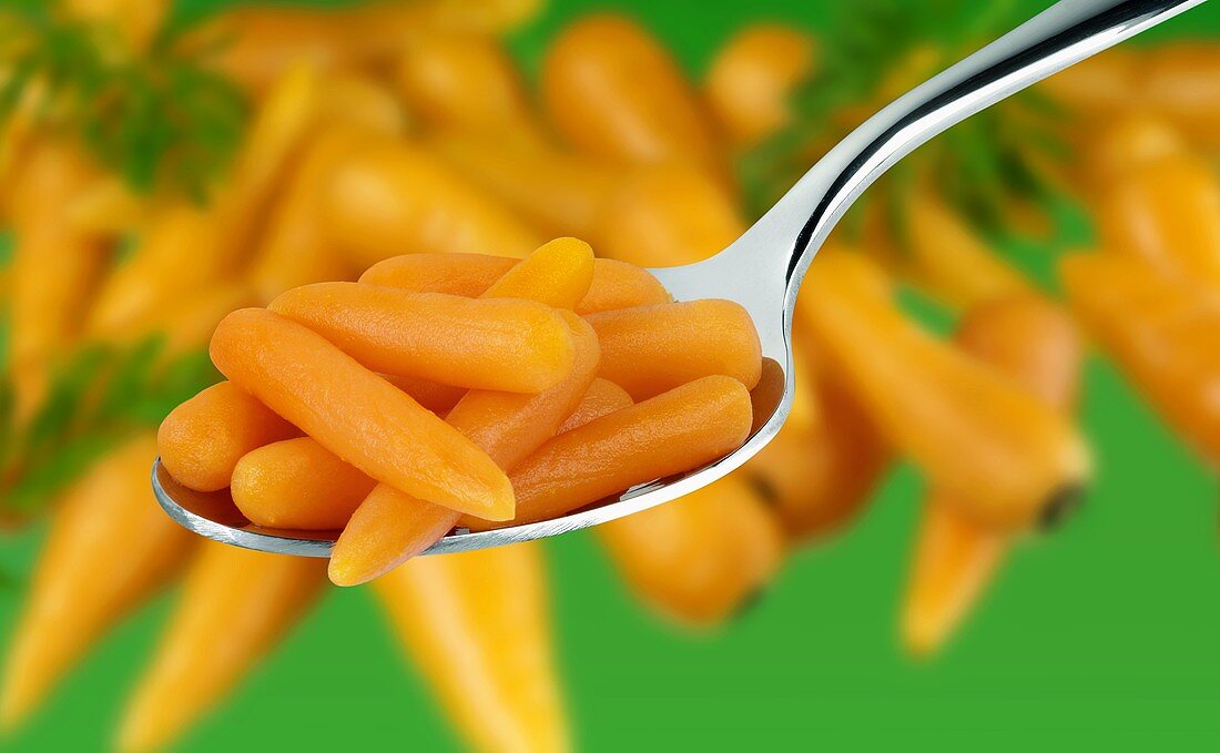 Baby carrots on a spoon and in background