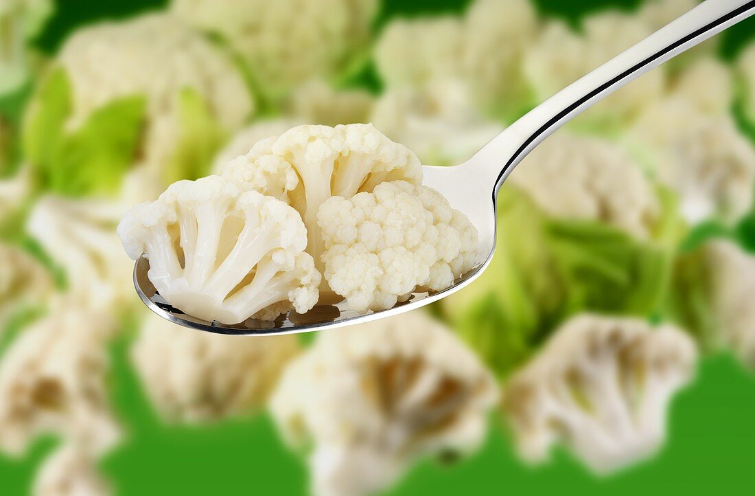 Cauliflower florets on a spoon and in background