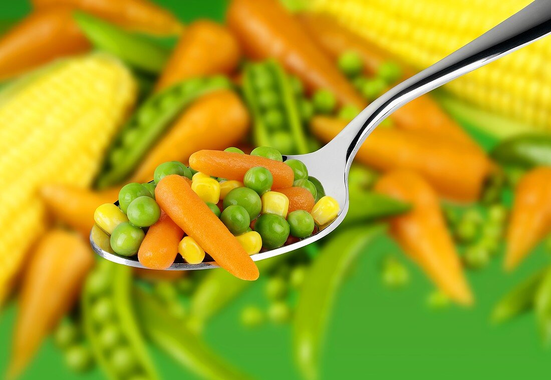 Peas, sweetcorn and carrots on a spoon