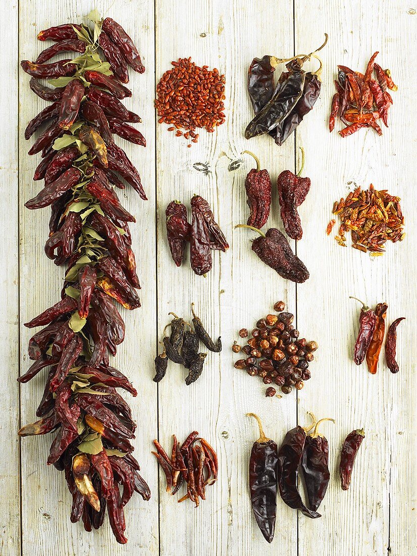 Various types of dried chillies on light wooden background