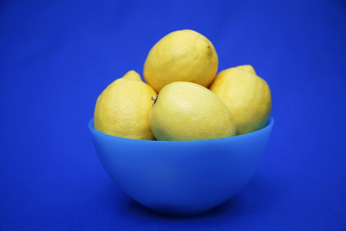 Lemons in a bowl against a blue background