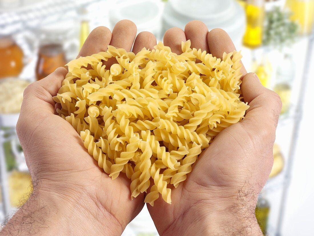 Two hands holding spiral pasta