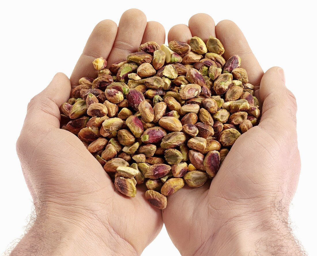 Hands holding shelled pistachios