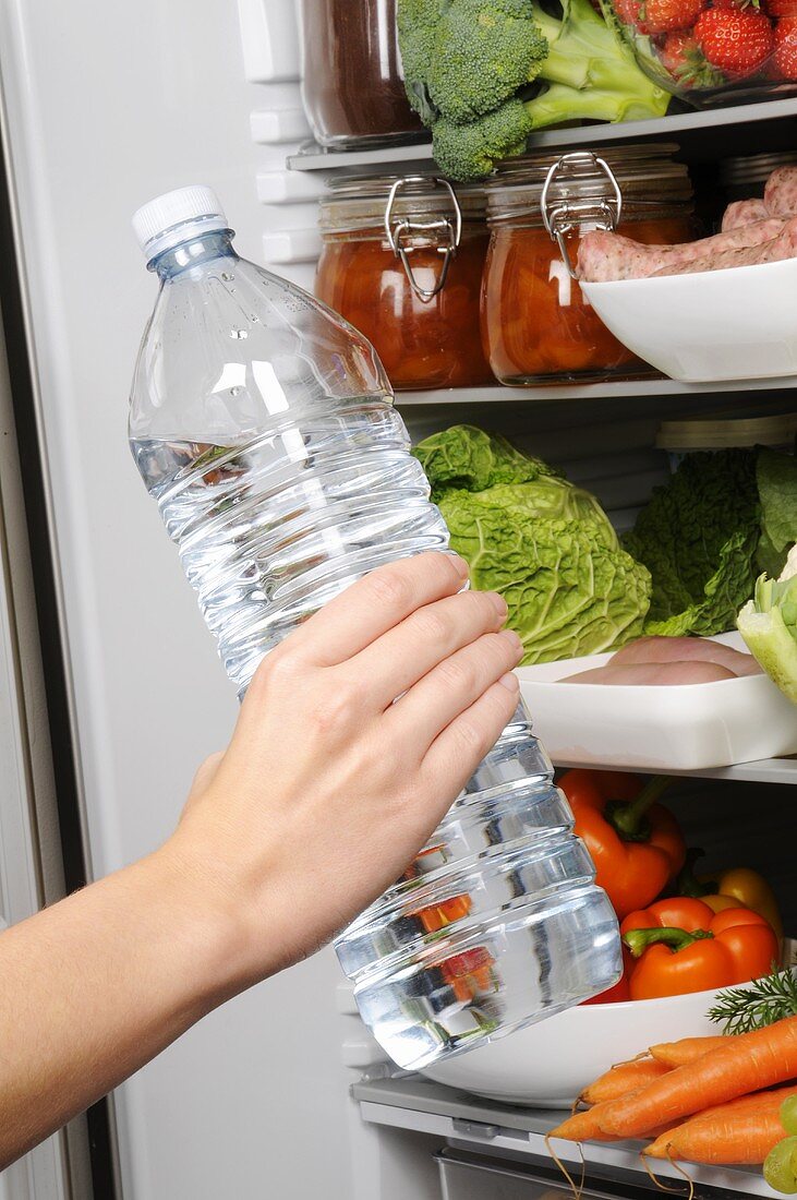 Eine Flasche Wasser in den Kühlschrank stellen