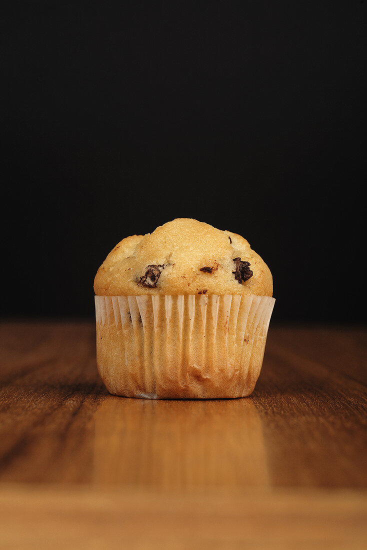 A chocolate chip muffin on a wooden background