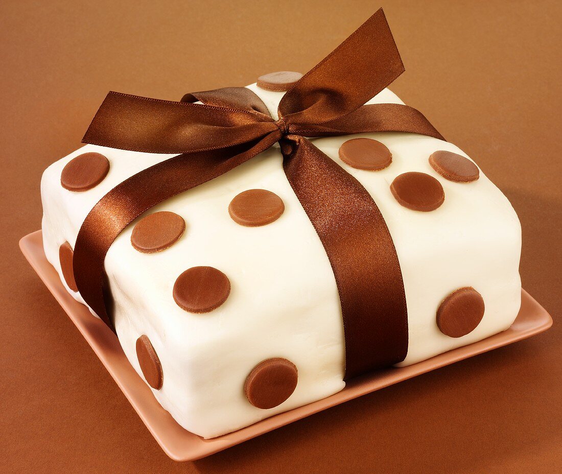 Cake covered in fondant icing, with spots and bow