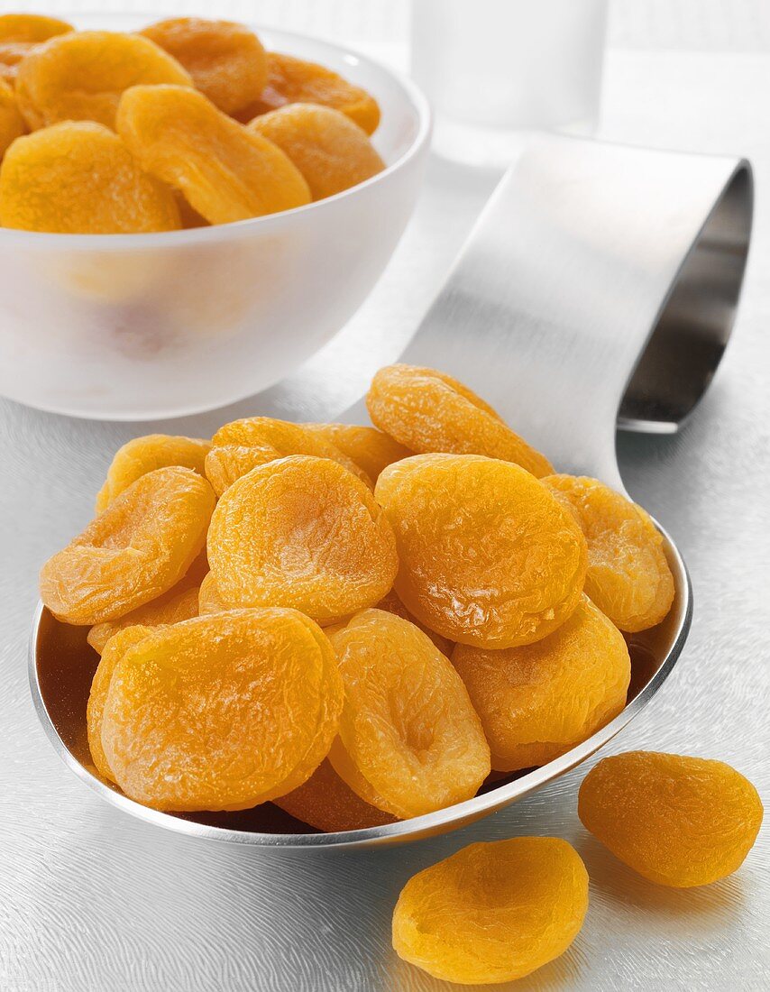 Dried apricots on a spoon and in a bowl