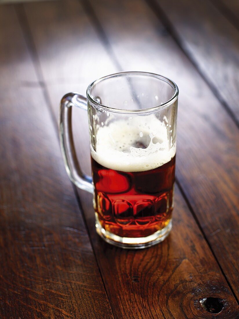 Half-full glass of beer on wooden background