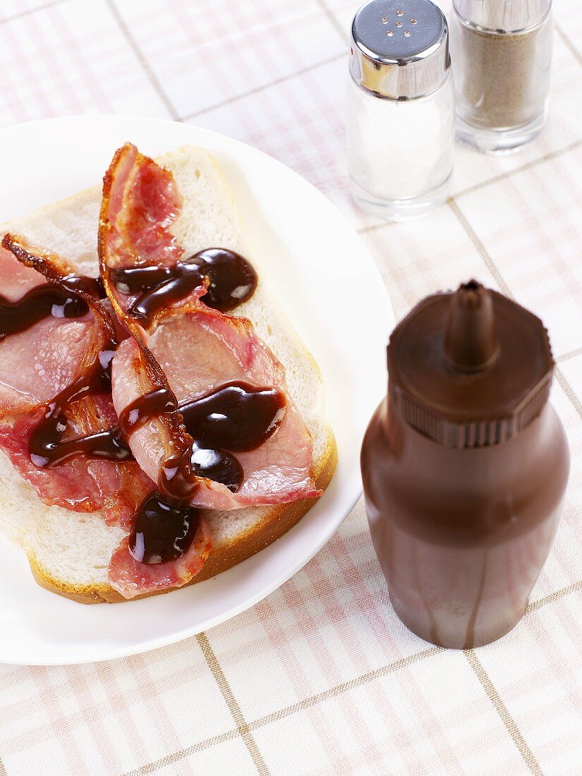 Gebratene Speckscheiben auf Toastbrot mit Würzsauce