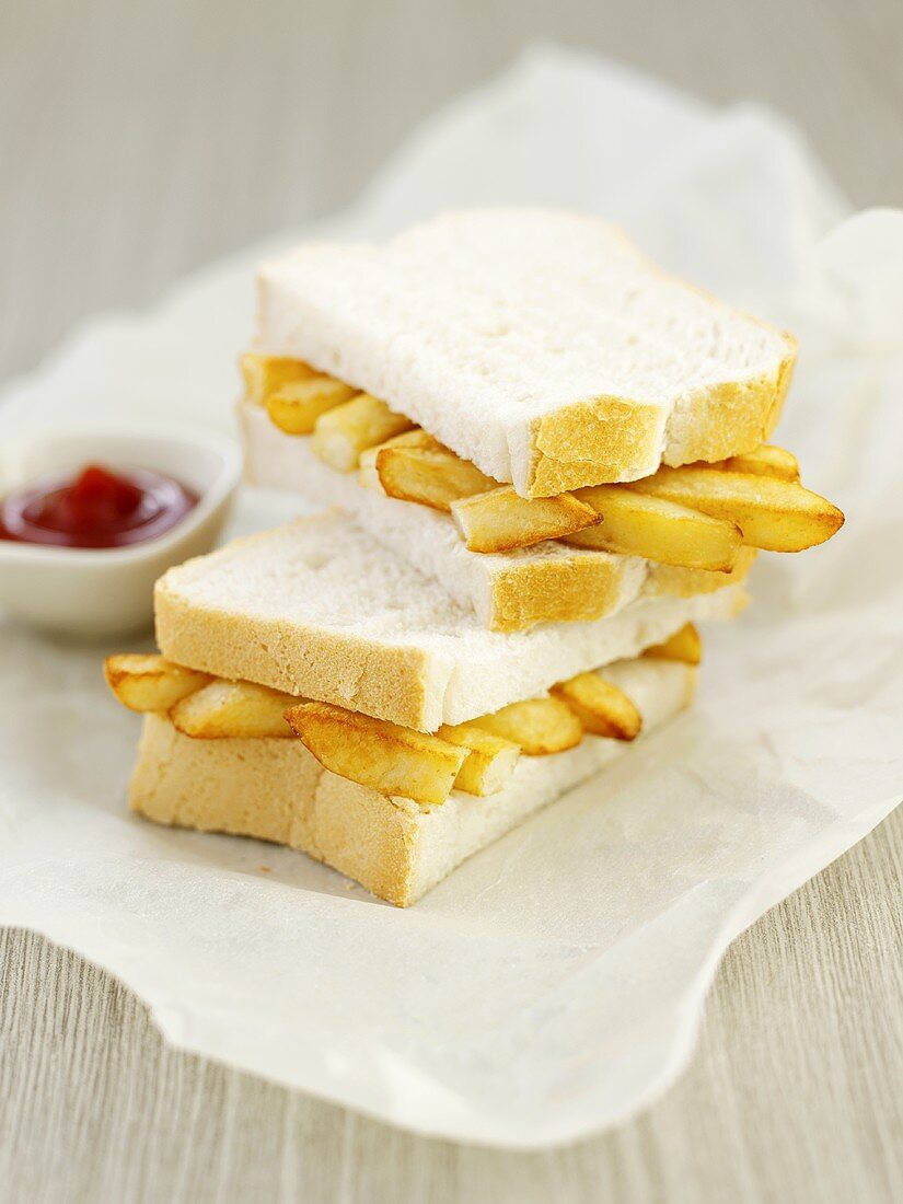Chip butty, halved, on paper with dish of ketchup