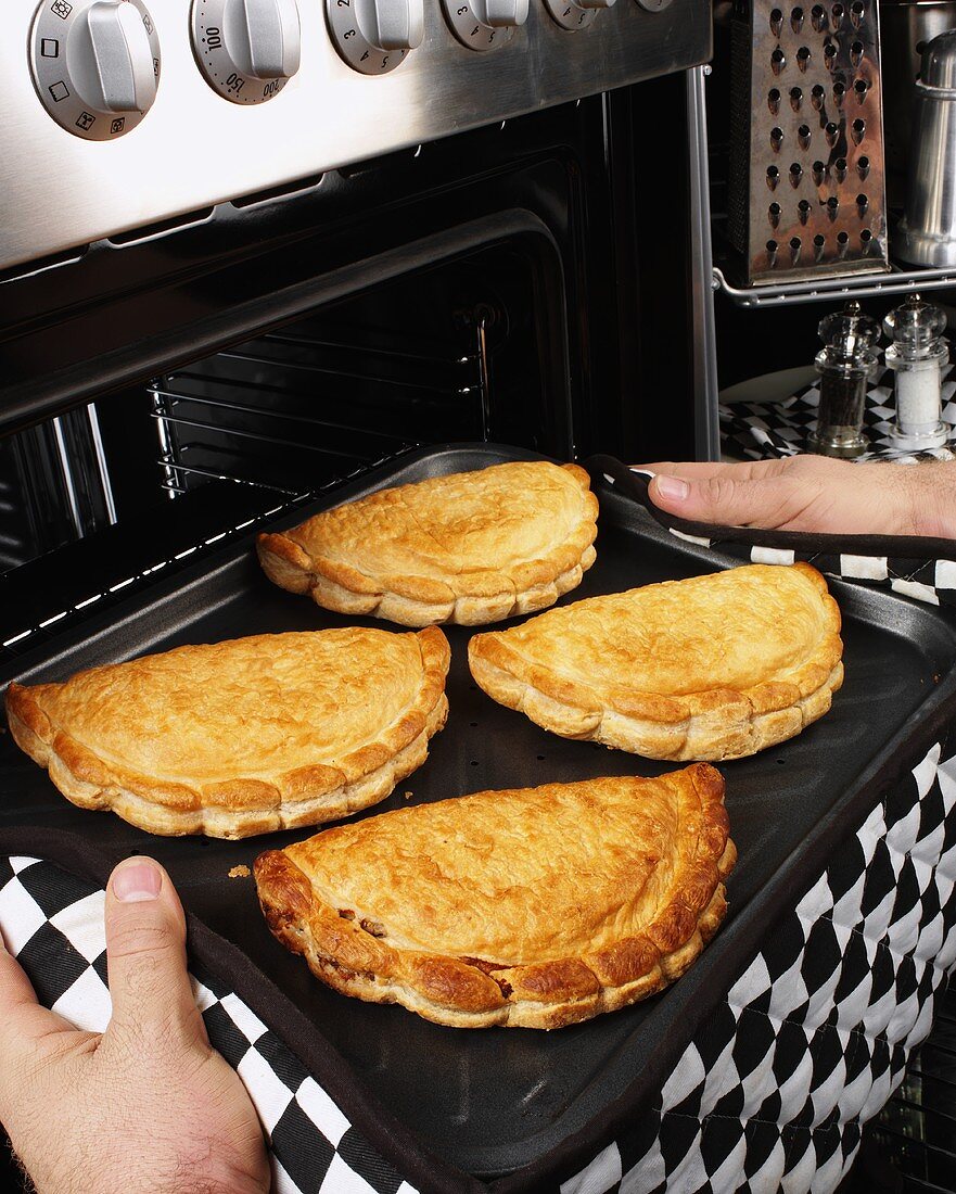 Man taking Cornish pasties out of the oven
