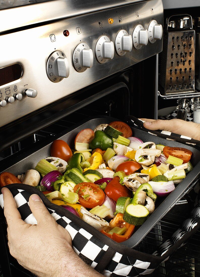 Man putting mixed vegetables into the oven