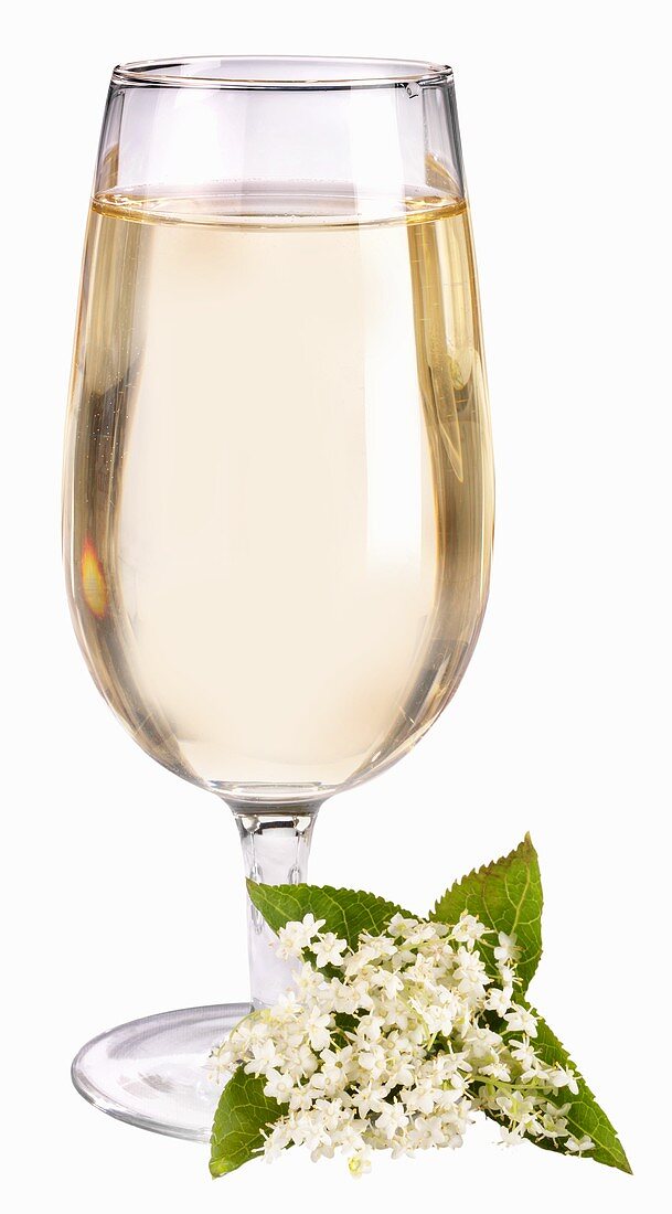 A glass of elderflower lemonade with elderflowers