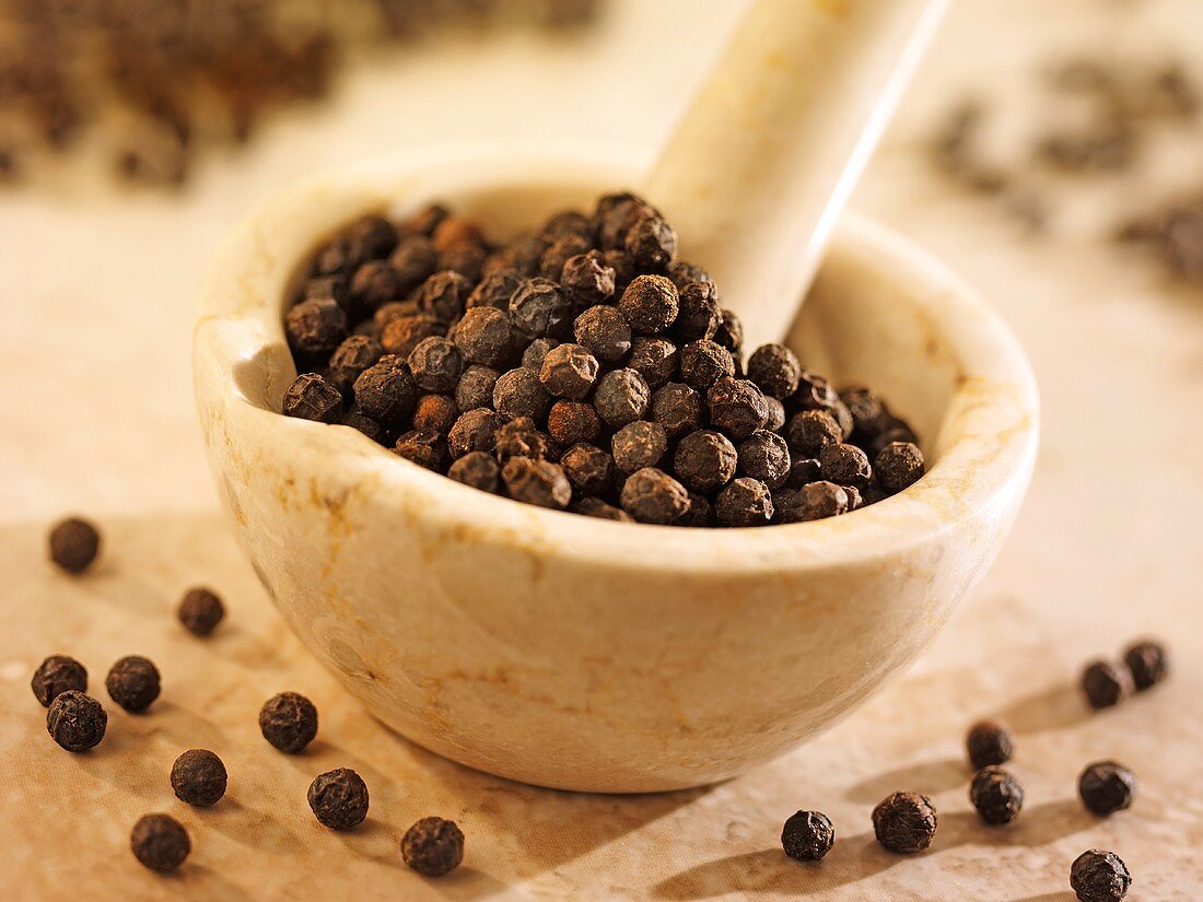 Black peppercorns in and beside a mortar