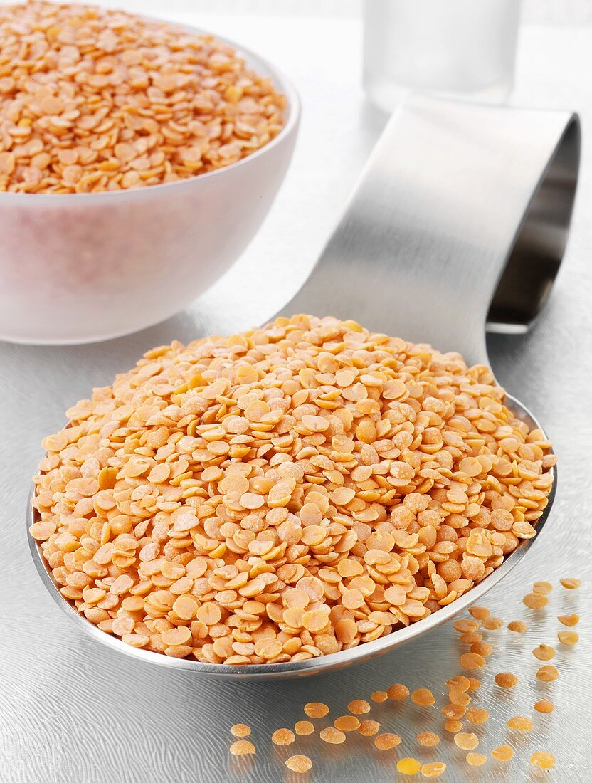 Red lentils on a spoon and in a glass bowl