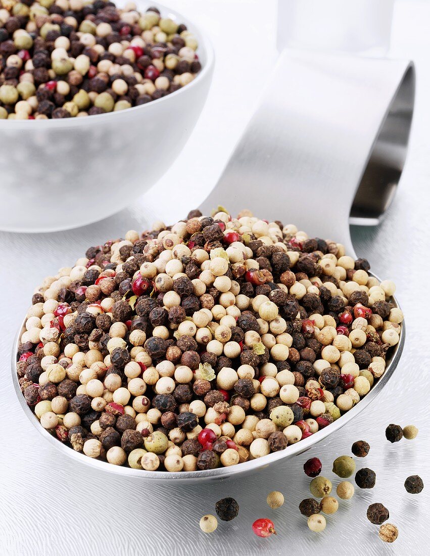 Mixed peppercorns on a spoon and in a glass bowl