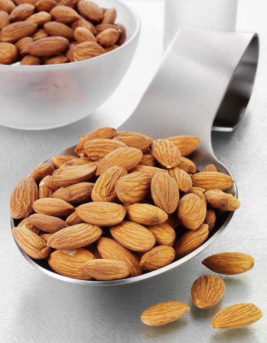 Shelled almonds on a spoon and in a glass bowl