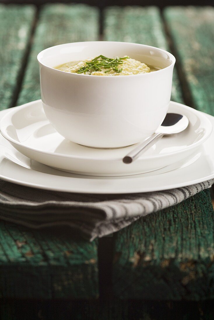 Pea soup with chives in a bowl on wood