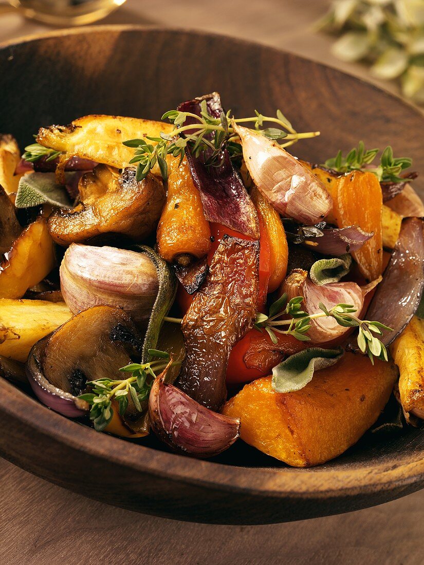 Roasted vegetables with herbs in a wooden bowl