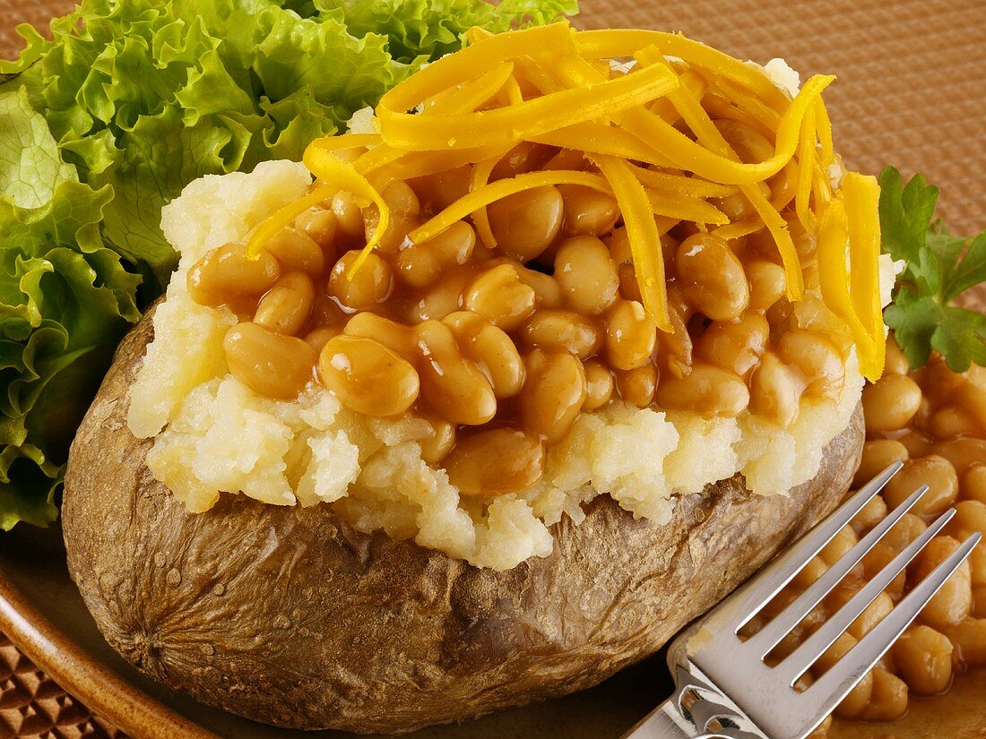A baked potato with baked beans and Cheddar cheese