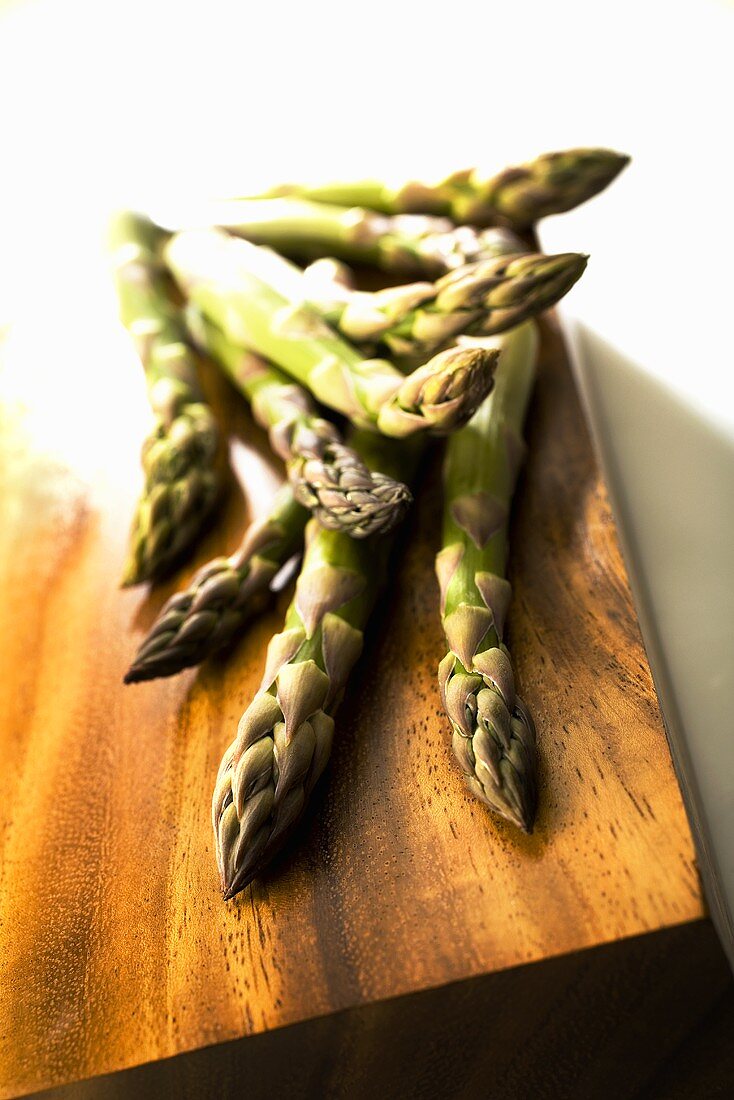 Several asparagus spears on wooden background