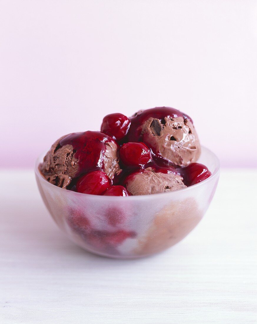 Chocolate ice cream with cherry sauce in a glass bowl
