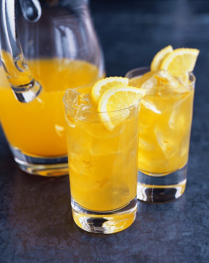 Glaskanne und zwei Gläser mit Orangenlimonade