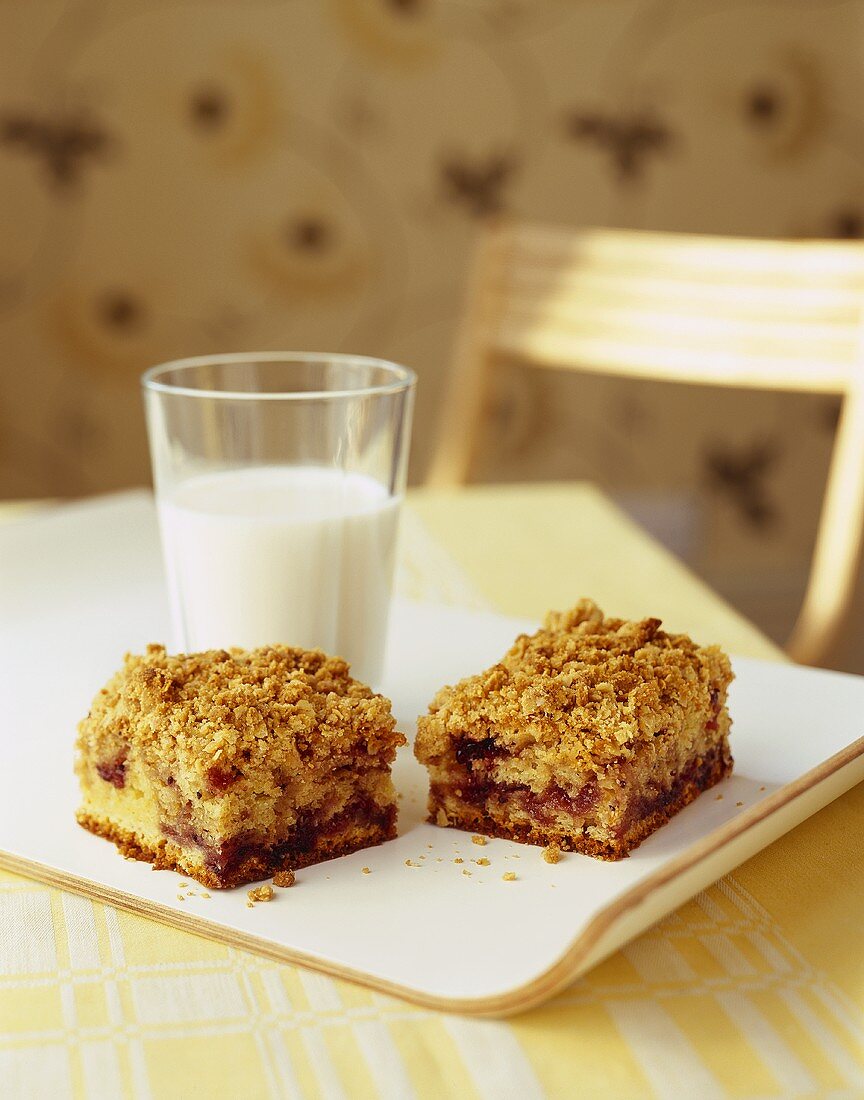 Two pieces of redcurrant crumble cake with a glass of milk