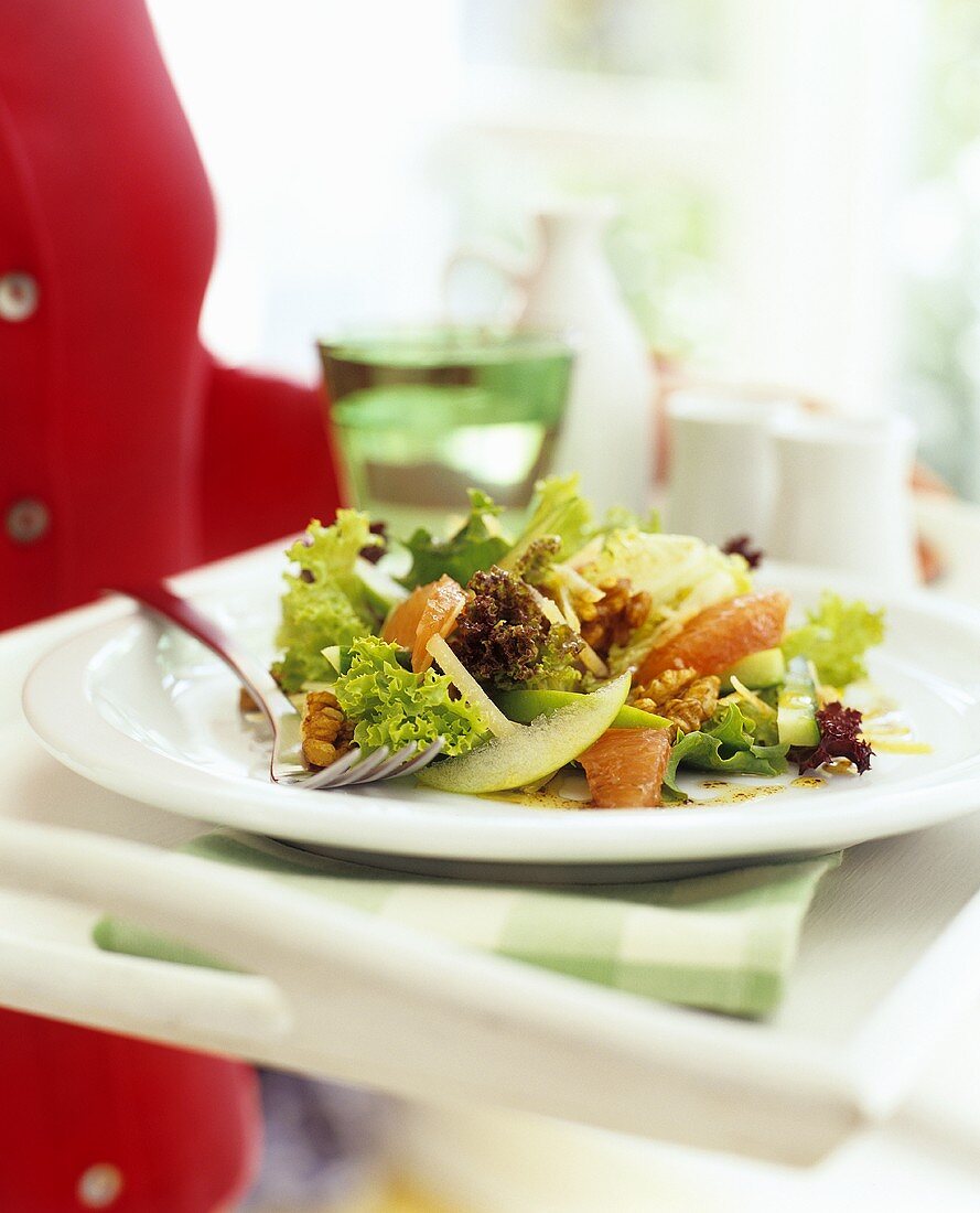 A woman carrying a tray with a colourful mixed salad