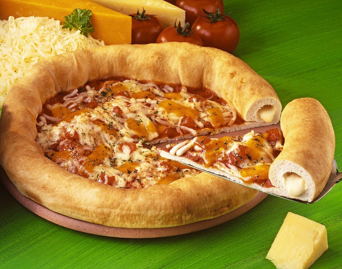Three cheese pizza, a slice cut, surrounded by ingredients