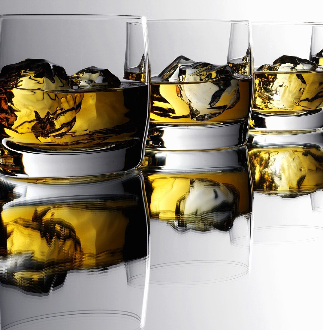 Three glasses of whisky with ice cubes