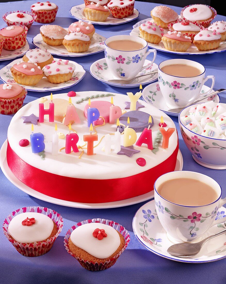 Geburtstagstorte mit Kerzen, Cupcakes und Tee
