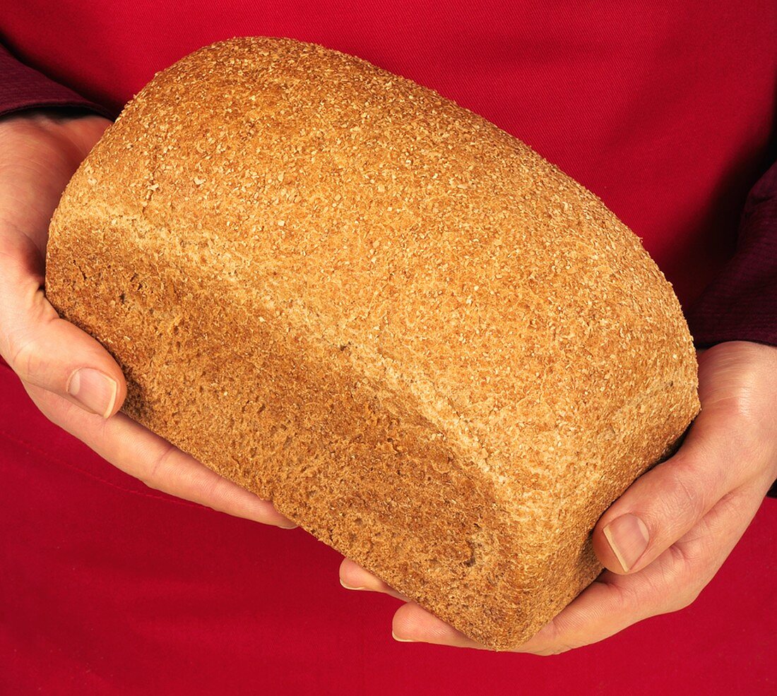 Hands holding a tin loaf