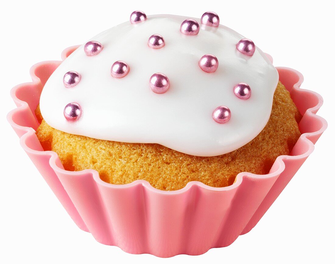 Cupcake mit weisser Glasur und rosa Zuckerperlen