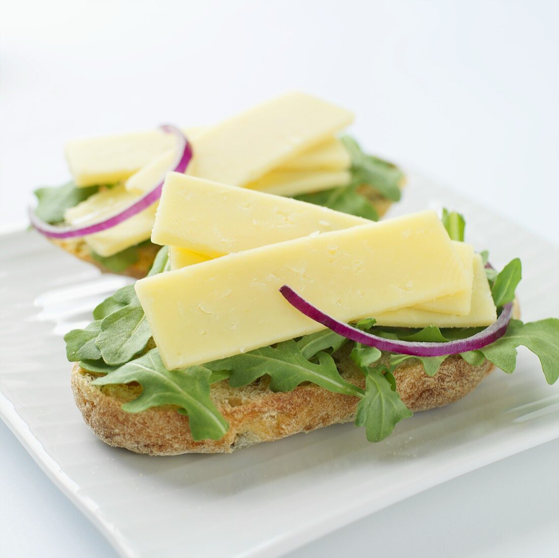 Cheddar cheese, rocket and red onion on bread rolls