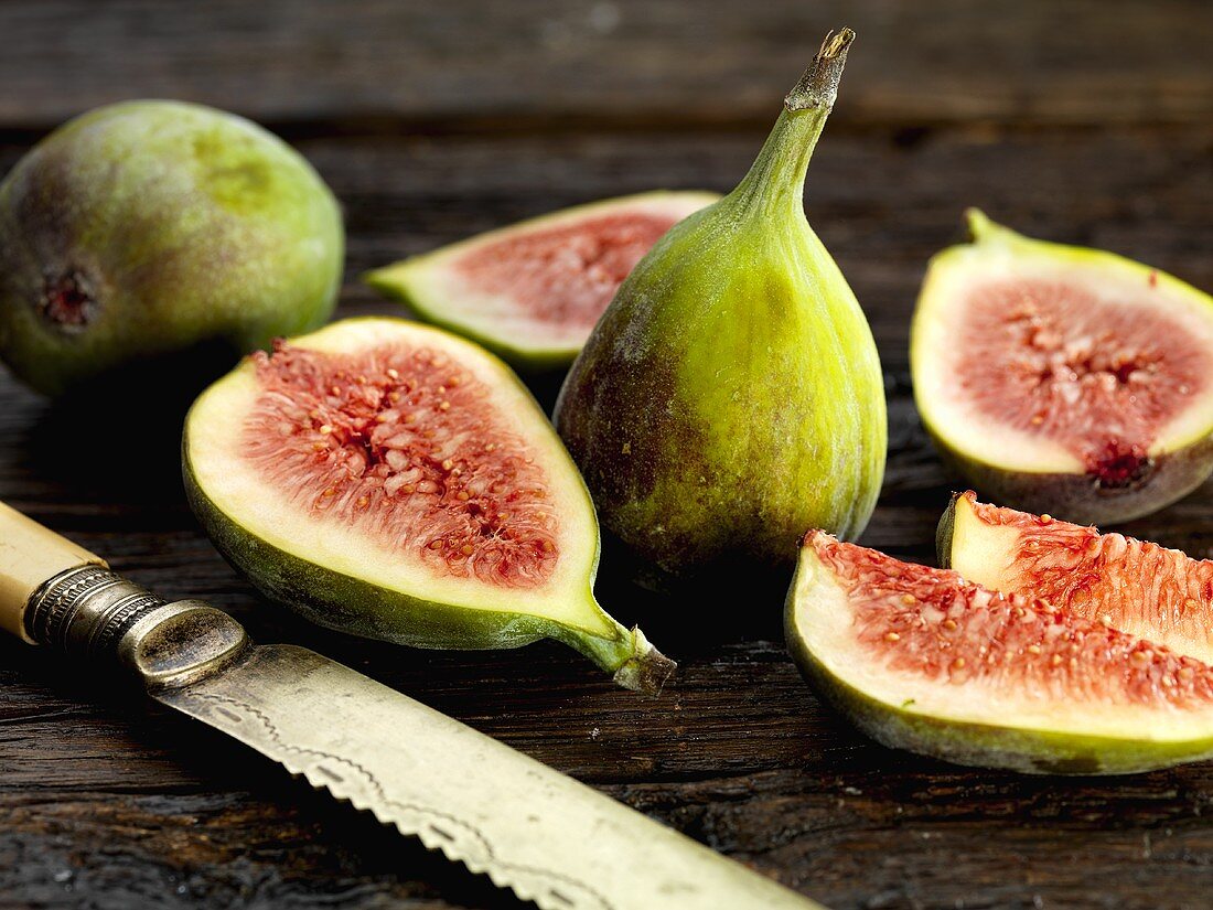 Fresh figs, whole & cut into pieces, on wooden background