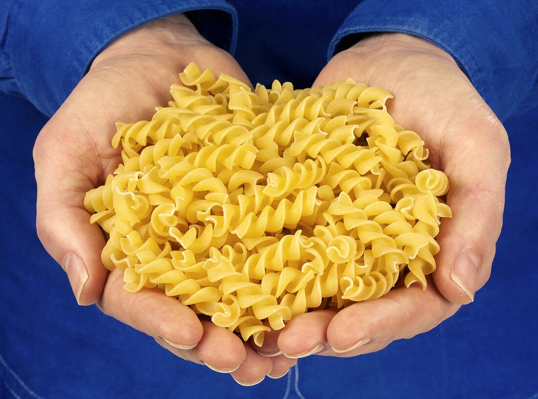 Hands holding spiral pasta