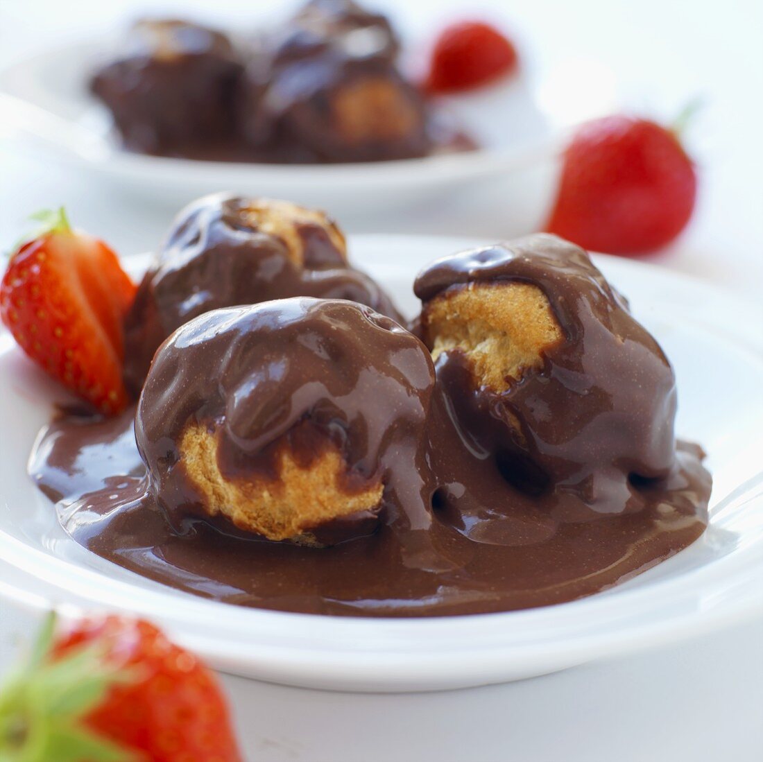 Profiteroles with chocolate sauce and strawberries