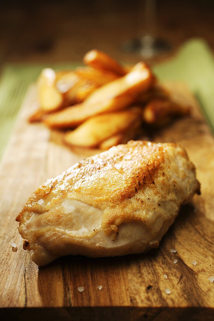 Hähnchenbrust mit Pommes frites auf Schneidebrett