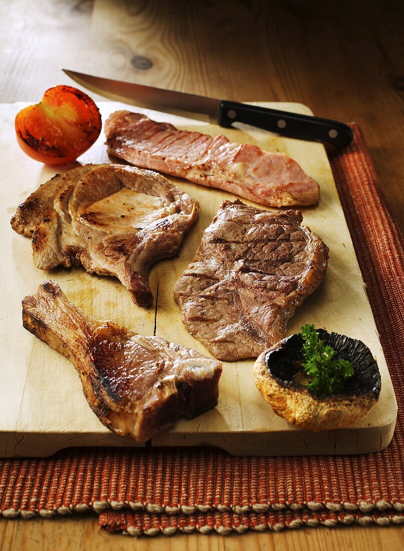 Assorted grilled steaks and chops on chopping board