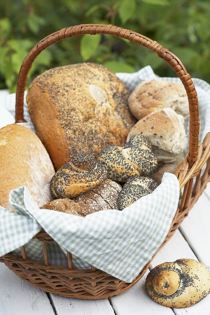 Verschiedene Brote und Brötchen im Korb auf Gartentisch