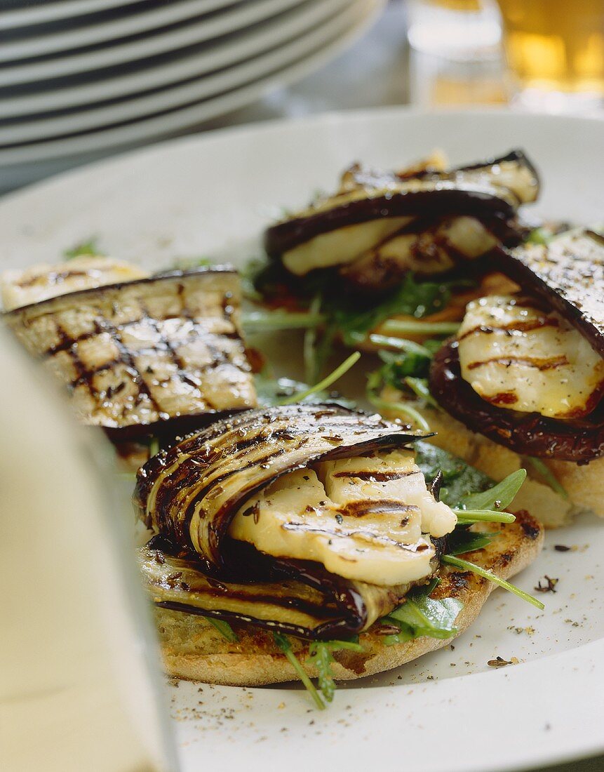 Grilled aubergine slices with halloumi on caraway crostini