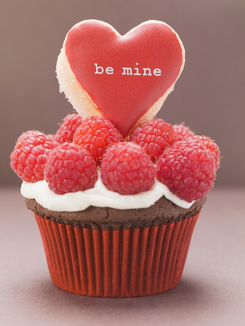 Chocolate cupcake with raspberries & heart-shaped biscuit