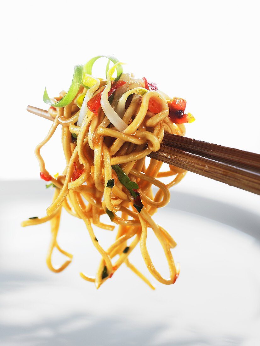 Fried egg noodles with vegetables on chopsticks